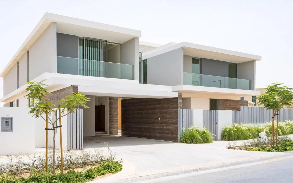 Contemporary two-storey villa in Dubai Hills Estate with deep eaves, timber cladding, glass balustrades and ornamental grass planting to the street.