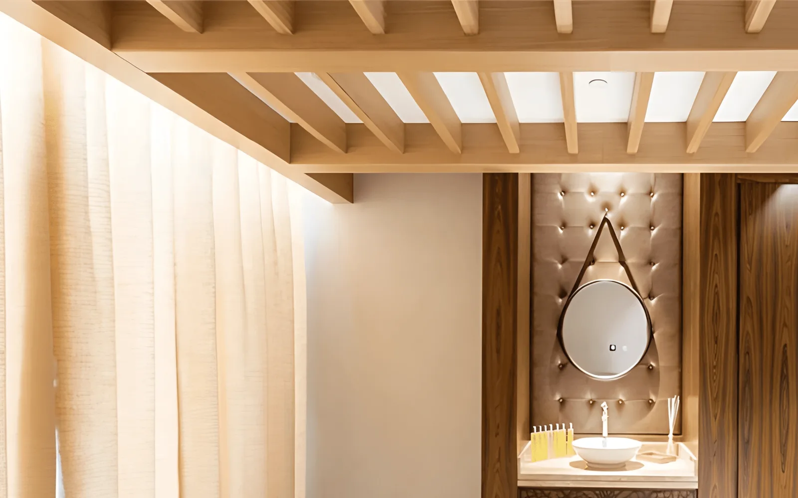 Pale timber batten ceiling raft with concealed lighting and skylights above a sheer linen curtain, walnut veneer joinery and an upholstered buttoned panel.